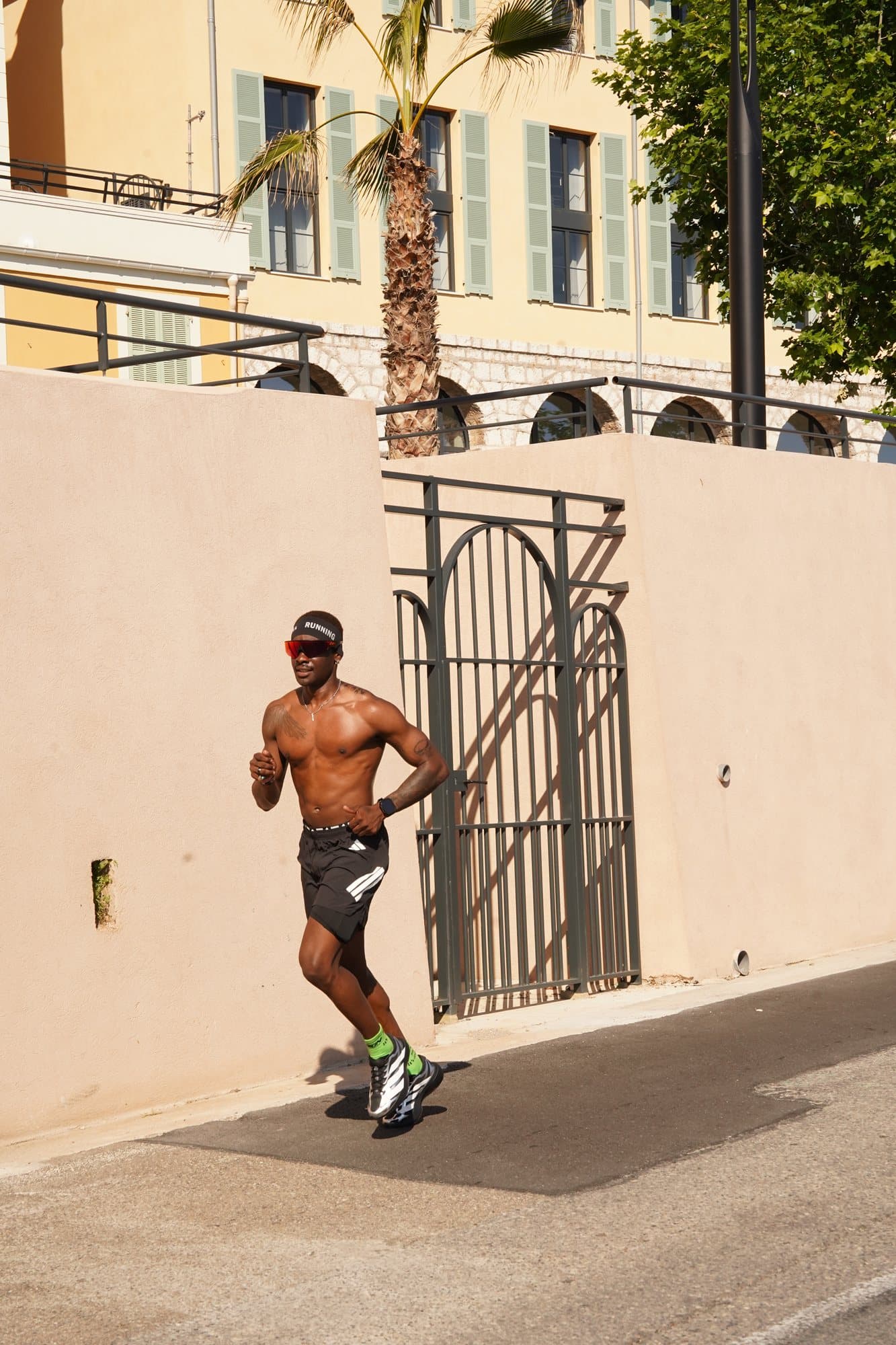 Le coach en footing au soleil le long d’un mur ocre, en ville